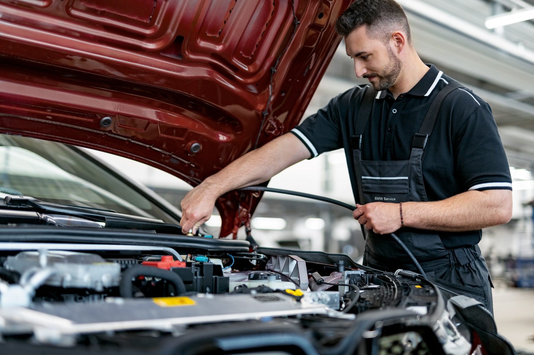 BMW service technician working under hood of BMW