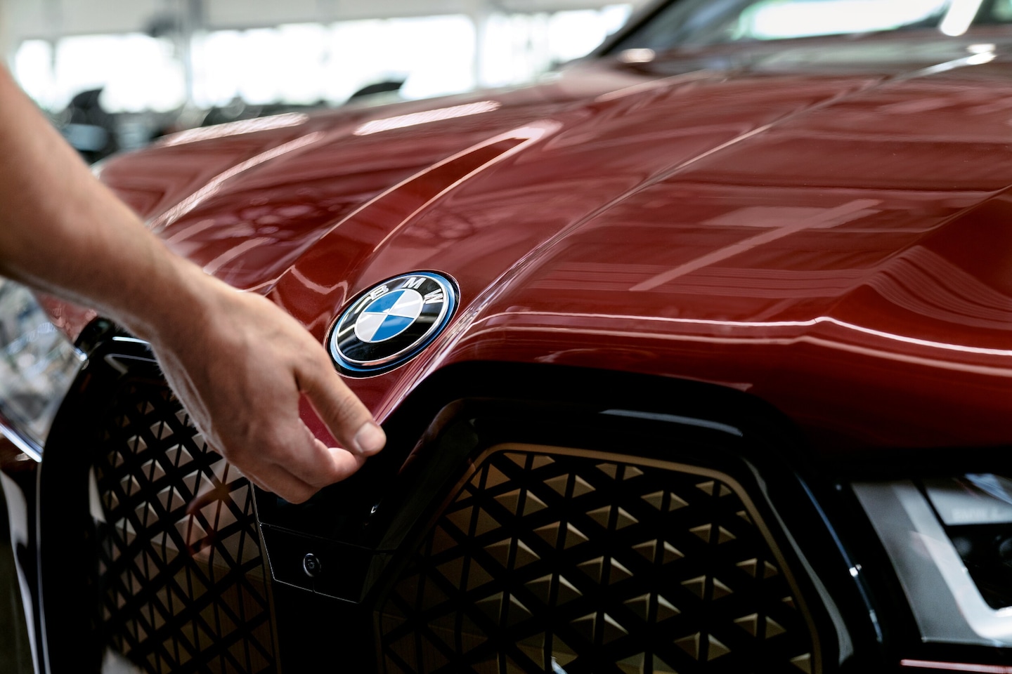 closeup of service technician closing hood of BMW