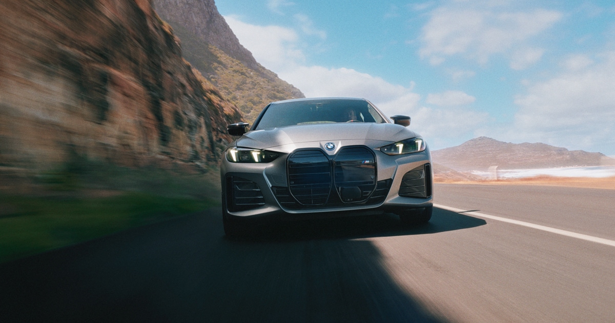 A BMW i4 driving towards the viewer on a road in the desert