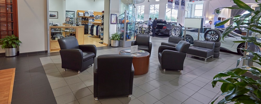Interior of BMW of Houston North featuring 4 cushioned chairs surrounding a table.