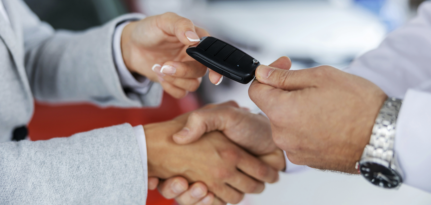 Customer receiving car keys during auto financing handshake