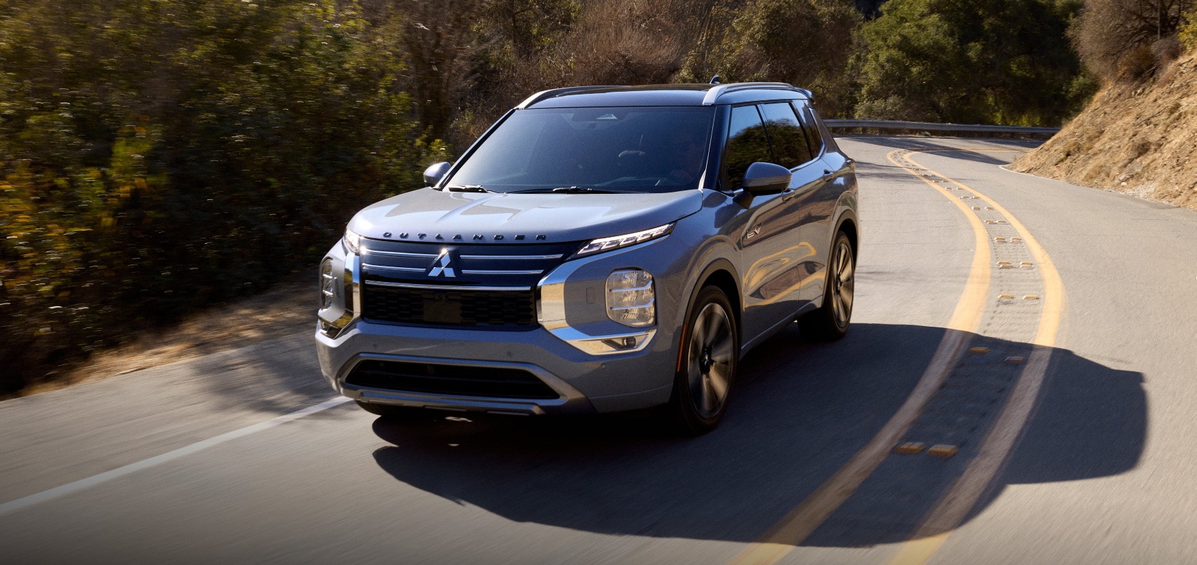 A%20grey%20Mitsubishi%20Outlander%20SUV%20taking%20a%20curve%20on%20a%20mountain%20road.png