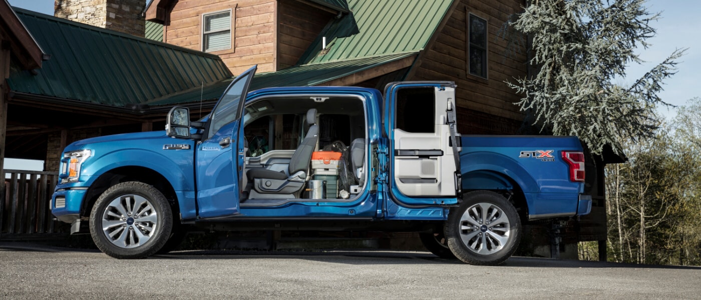 A blue 2020 Ford F-150 filled with luggage and the doors open
