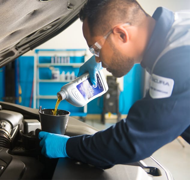 Benefits of Changing Your Acura’s Oil at Bobby Rahal Acura in Mechanicsburg | Acura Service Advisor Pouring New Oil Into Vehicle