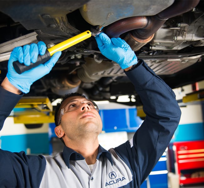 Benefits of Changing Your Acura’s Oil at Bobby Rahal Acura in Mechanicsburg | Acura Service Advisor Loosening Bolt on Oil Try to Drain Old Oil