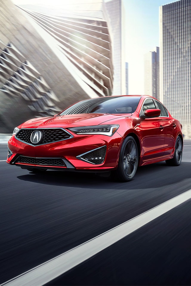 Leasing versus Buying a Acura at Bobby Rahal Acura in Mechanicsburg, PA | Red Acura ILX A-Spec Driving in the City Facing Left Towards Camera