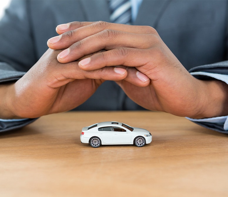 Defining GAP Insurance at Bobby Rahal Acura in Mechanicsburg | Finance Advisor Sitting at Desk with Hands Folded over Toy Car