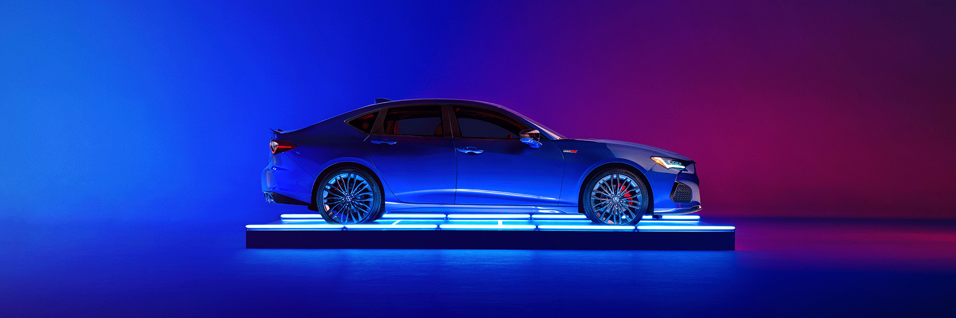 All-New 2022 Acura TLX at Bobby Rahal Acura | Profile View of Apex Blue Pearl 2022 Acura TLX on Platform with Neon Blue Lights on Left and Neon Red Lights on Right