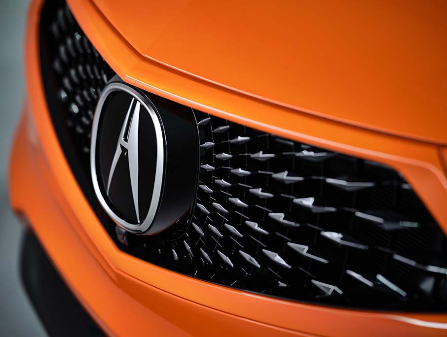 Compare the 2021 Acura RDX vs. the 2022 Audi Q5 at Bobby Rahal Acura | Close-Up Shot of Carbon Fiber Grille & Acura Emblem on Front-End of an Orange 2021 Acura RDX
