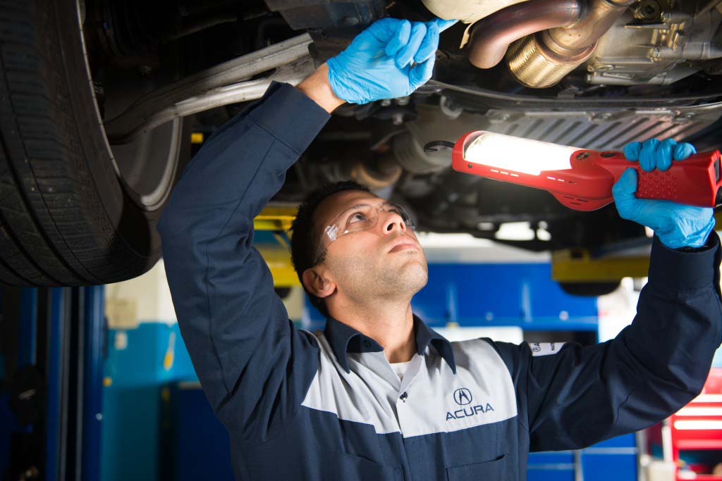 Basic Car Maintenance and Servicing Checklist | Bobby Rahal Acura | Acura service technician checking exhaust for any leaks