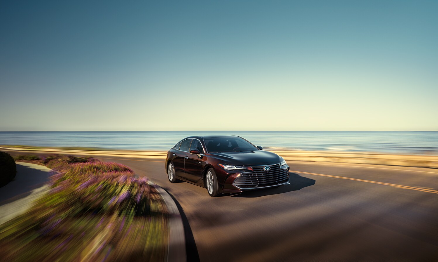 Toyota Hybrid for Everyone at Bobby Rahal Toyota | 2022 Toyota Avalon Hybrid driving on a road along the coast