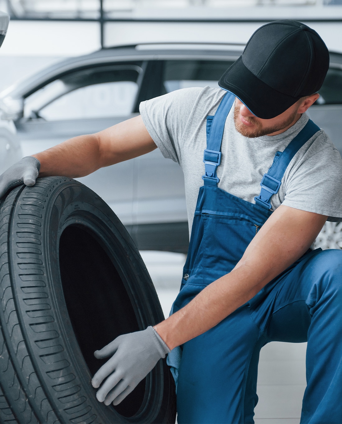 Winter Tires vs. All Season Tires at Bobby Rahal Toyota in Mechanicsburg, PA | Mechanic in blue uniform examining an all season tire