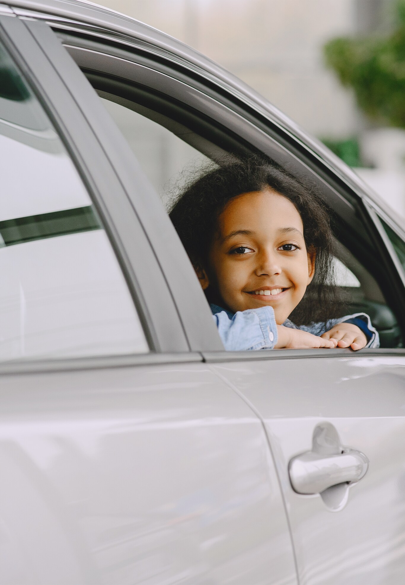 Best Time To Buy At Bobby Rahal Toyota in Mechanicsburg, PA | Little girl is happy and smiling while sitting in the passenger side window of a new grey color car