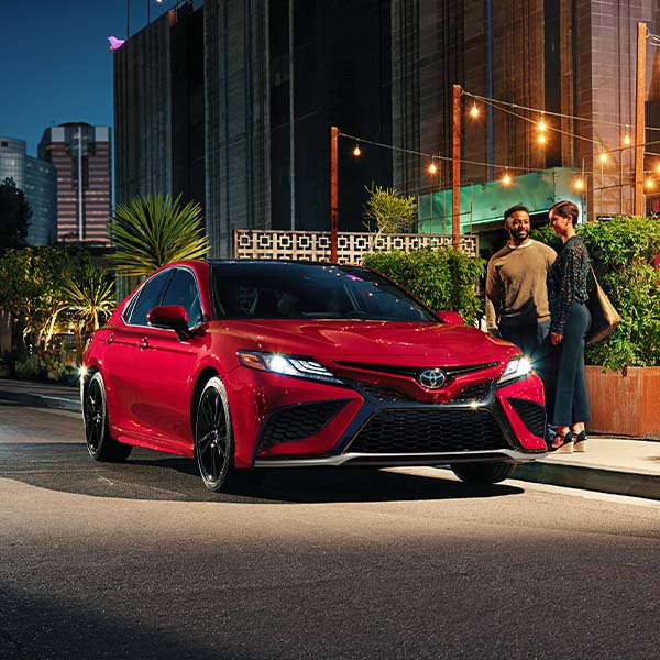 Model Features of the 2022 Toyota Camry at Bobby Rahal Toyota | Red 2022 Toyota Camry Street Parked Next to Outdoor Bar in City at Night