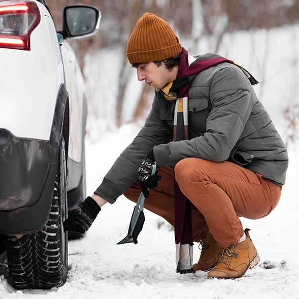How to prepare your Toyota for the winter season in Mechanicsburg, PA at Bobby Rahal Toyota | Man outside in the cold weather checking the tire pressure of his car 