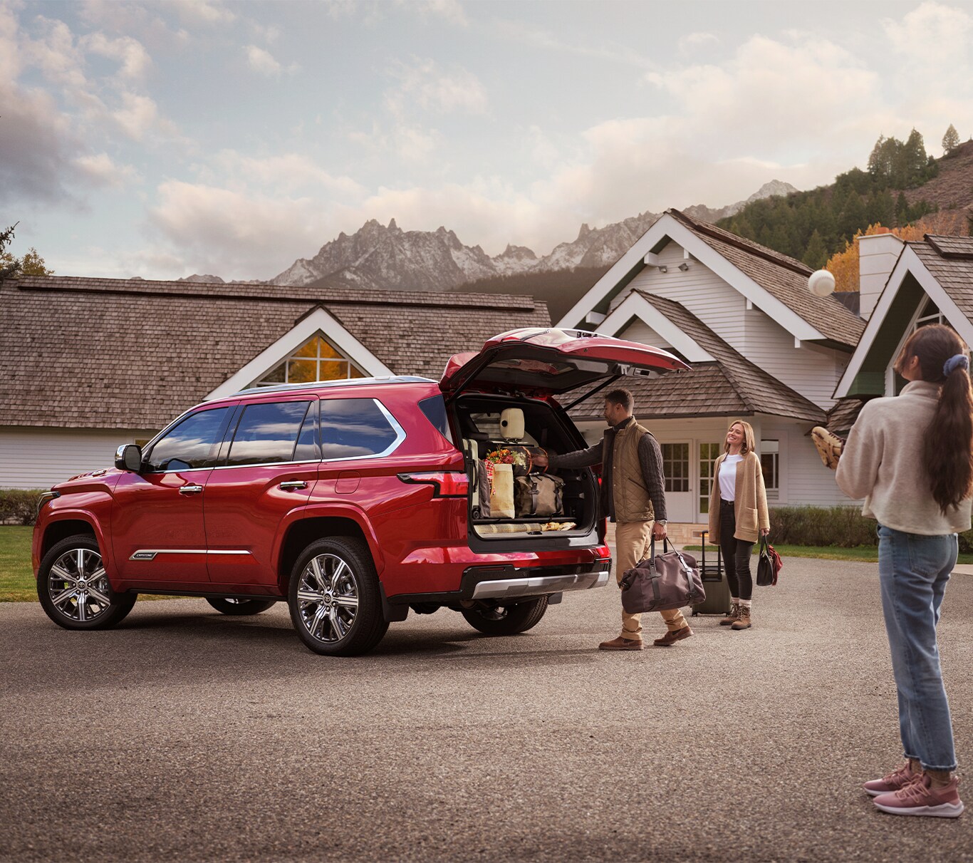2023 Toyota Sequoia vs. 2023 Chevrolet Tahoe at Bobby Rahal Toyota | Red 2023 Toyota Sequoia with the trunk open and a family loading thier belonging into it 