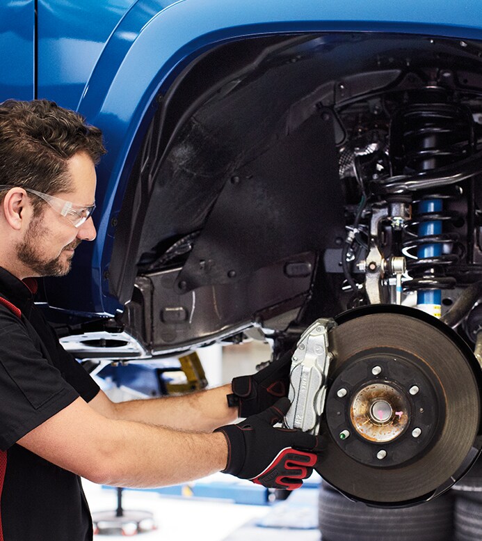 Brake replacement and Safety at Bobby Rahal Toyota | Mechanic with safety glasses is removing rear brake caliper
