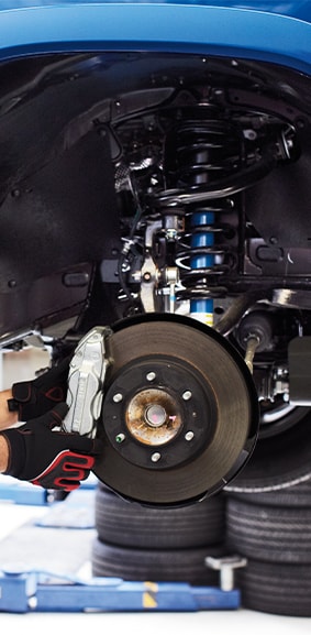 ToyotaCareAt Bobby Rahal Toyota in Mechanicsburg, PA | Mechanic wearing protective gloves to install new brake pads for a Toyota Tacoma 