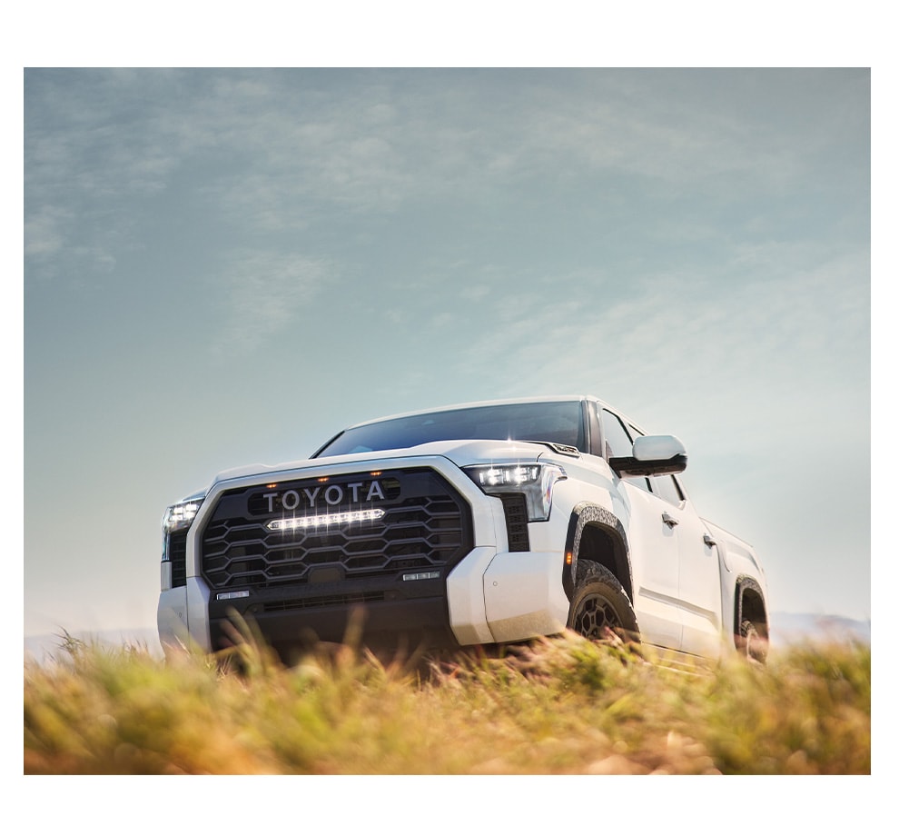 Car Technology Trends at Bobby Rahal Toyota in Mechanicsburg, PA | Front profile of a white 2023 Toyota Tundra parked on a hill with grass