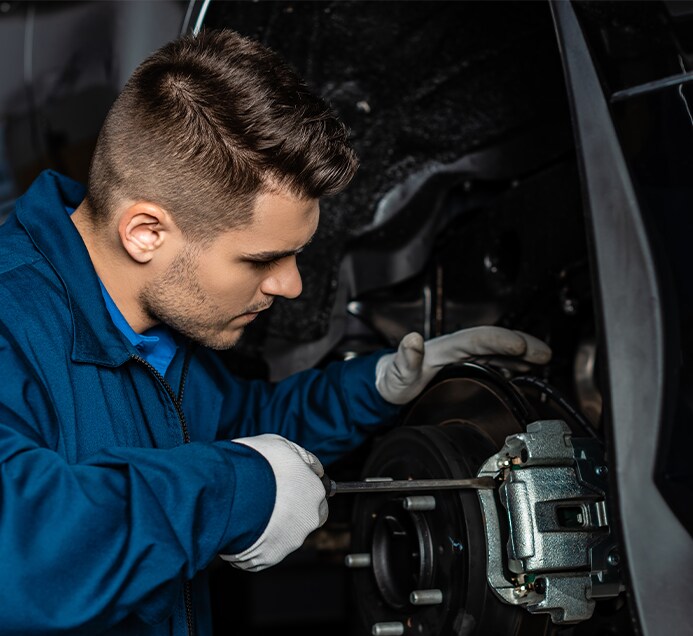 Brake replacement and Safety at Bobby Rahal Toyota | Mechanic in blue uniform is working on brake caliper  