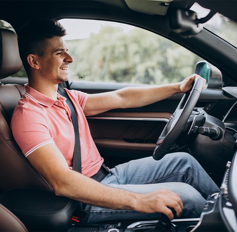 Enjoy A Test Drive At Bobby Rahal Toyota in Mechanicsburg, PA | Man in pink polo shirt is happy driving his car with his hand on the steering wheel