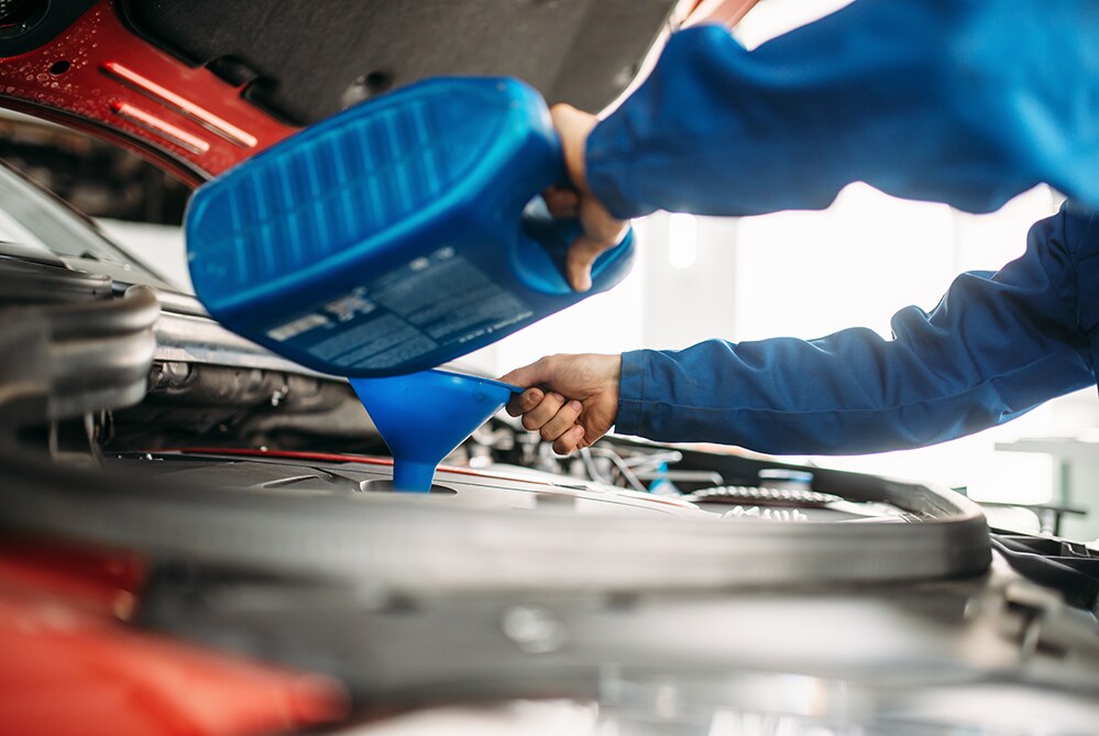 How to prepare your Toyota for the winter season in Mechanicsburg, PA at Bobby Rahal Toyota | Mechanic refilling oil in vehicle before winter