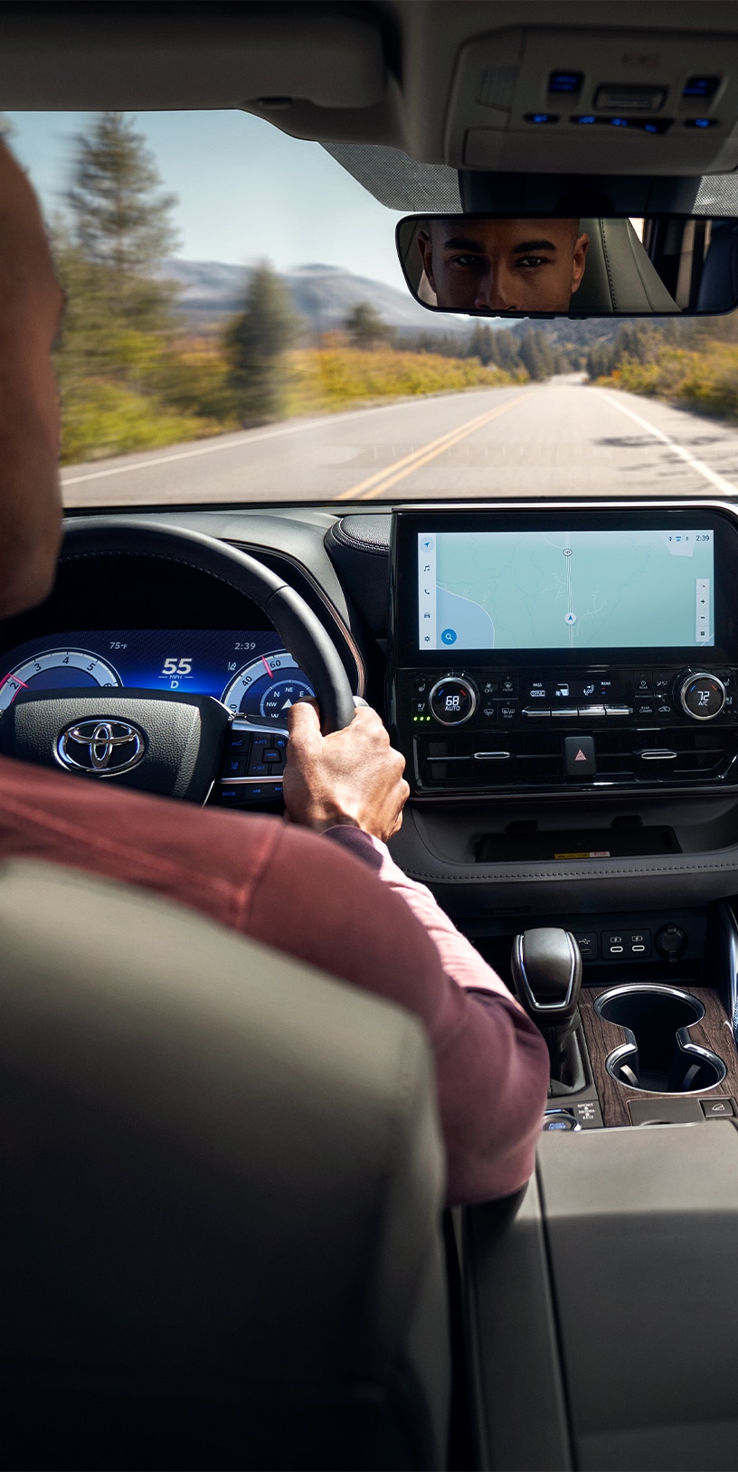 2023 Toyota Highlander at Bobby Rahal Toyota in Mechanicsburg, PA | Man in dark red shirt is sitting in the drivers seat and driving his 2023 Toyota Highlander during the day 