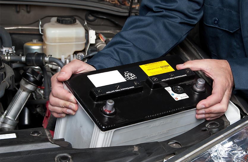 Everything You Need to Know about Your Car Battery at Bobby Rahal Toyota | Person in navy blue uniform installing new car battery into the engine bay
