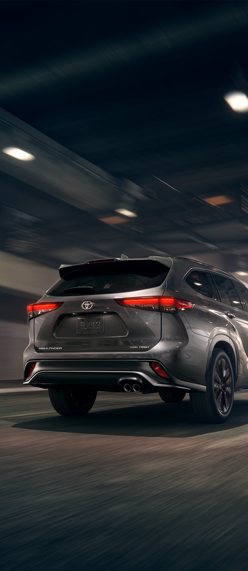 2023 Toyota Highlander at Bobby Rahal Toyota in Mechanicsburg, PA | Rear view of a grey 2023 Toyota Highlander driving down the road 