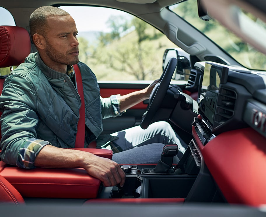 The All-New 2022 Toyota Tundra at Bobby Rahal Toyota in Mechanicsburg, PA | Man Driving Featuring Red Interior Upholstery