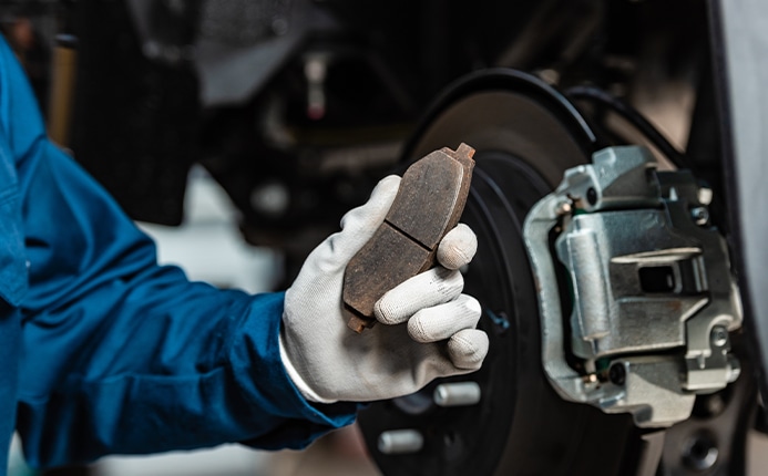 Brake replacement and Safety at Bobby Rahal Toyota | Mechanic in blue uniform and white gloves holding brake pads  