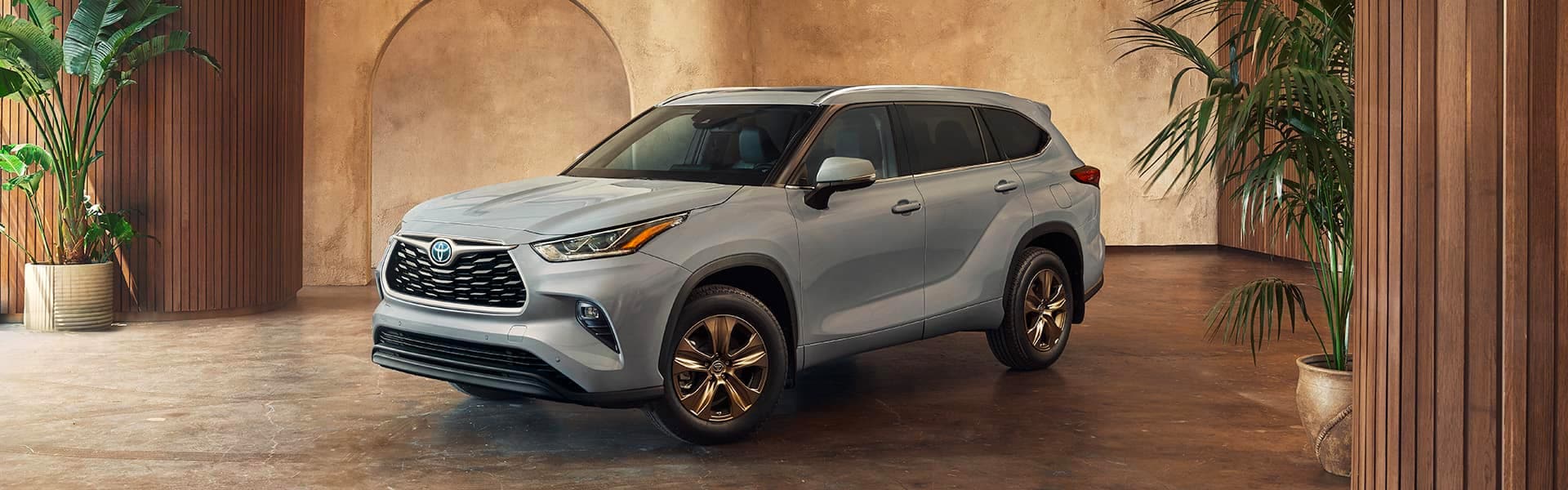 Model Features of the 2022 Toyota Highlander Hybrid at Bobby Rahal Toyota | Bronze Edition 2022 Highlander Hybrid Parked in Brown and Gold Showroom