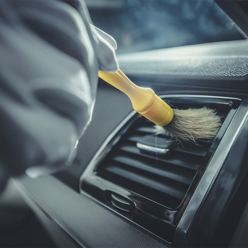 Accessories that help keep your Toyota protected at Bobby Rahal Toyota in Mechanicsburg, PA | Service Tech Dusting Off Air Vent in Vehicle