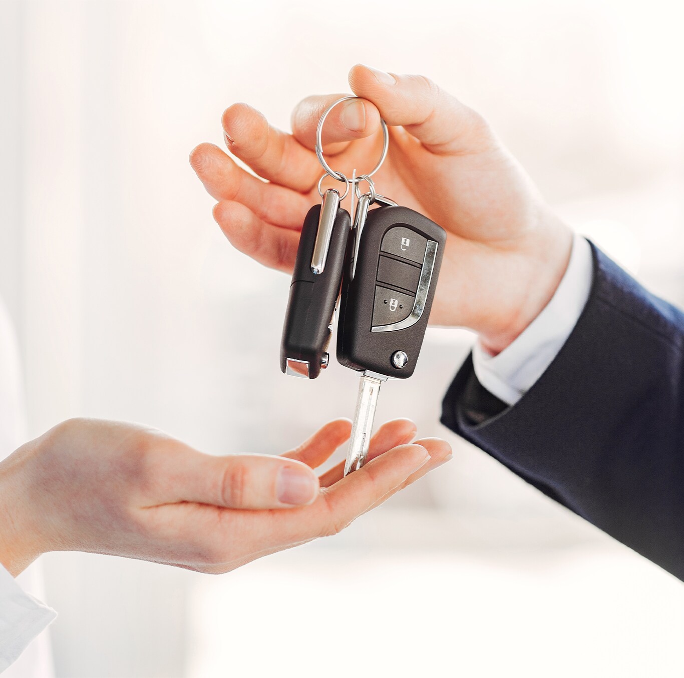 Best Time To Buy At Bobby Rahal Toyota in Mechanicsburg, PA | Man in black suit is handing over new car keys to the person on the left side 