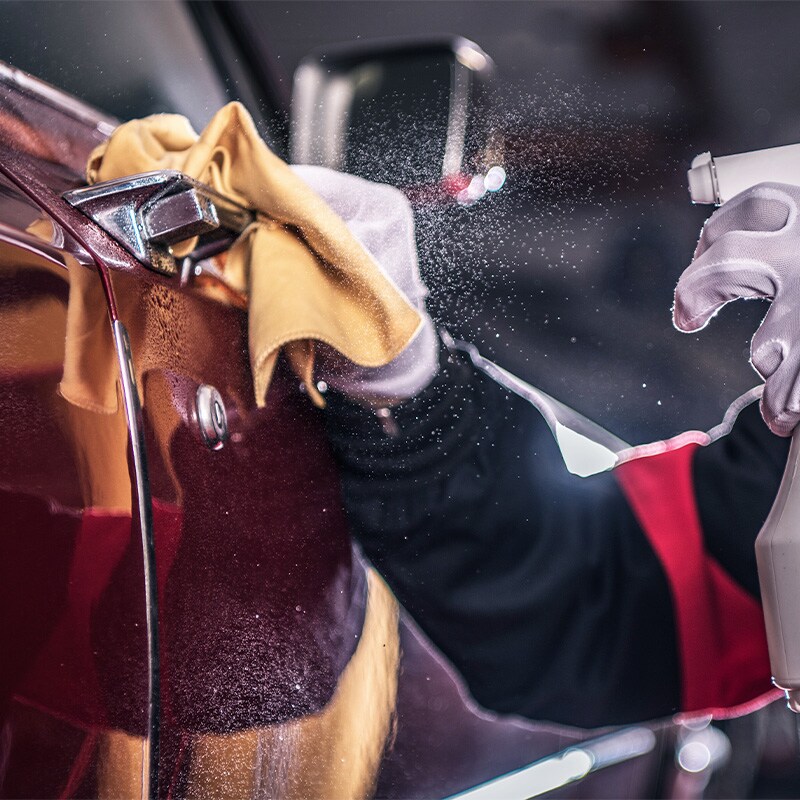 Accessories that help keep your Toyota protected at Bobby Rahal Toyota in Mechanicsburg, PA | Service Tech Spraying Cleaner on Car Door Handle