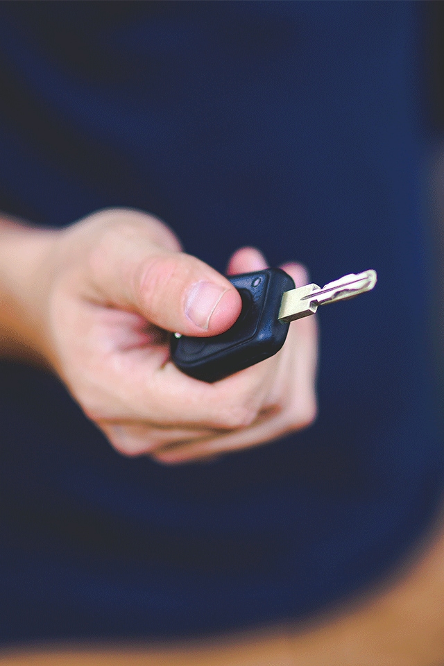 High Cost of Replacing a Car Key | Bobby Rahal Toyota | Person with Dark Blue Shirt and Brown Pants Holding Key Out in Front of Them