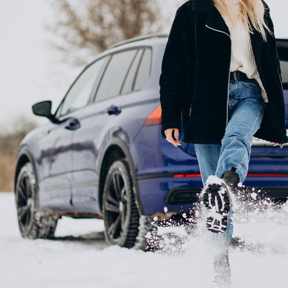 How to prepare your Toyota for the winter season in Mechanicsburg, PA at Bobby Rahal Toyota | Woman outside kicking some snow while in front of her blue color car 
