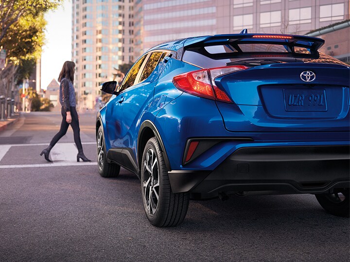 Blue C-HR stopped at a crosswalk for pedestrian