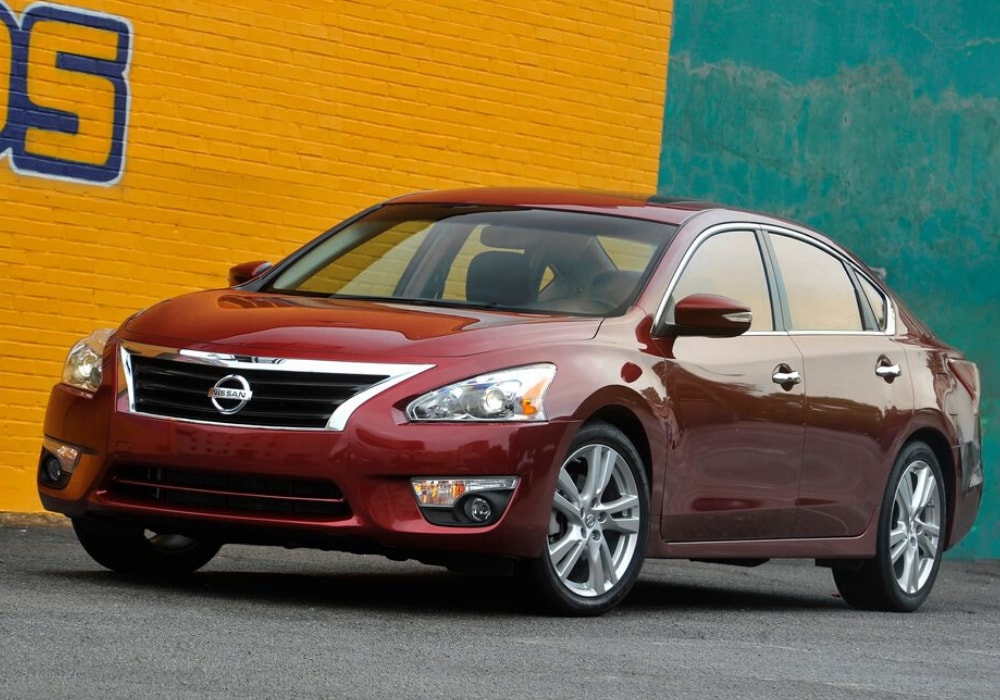 2013 Nissan Altima in red exterior color by a graffiti wall