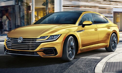 2020 Volkswagen Arteon gold yellow making a turn at a downtown city intersection