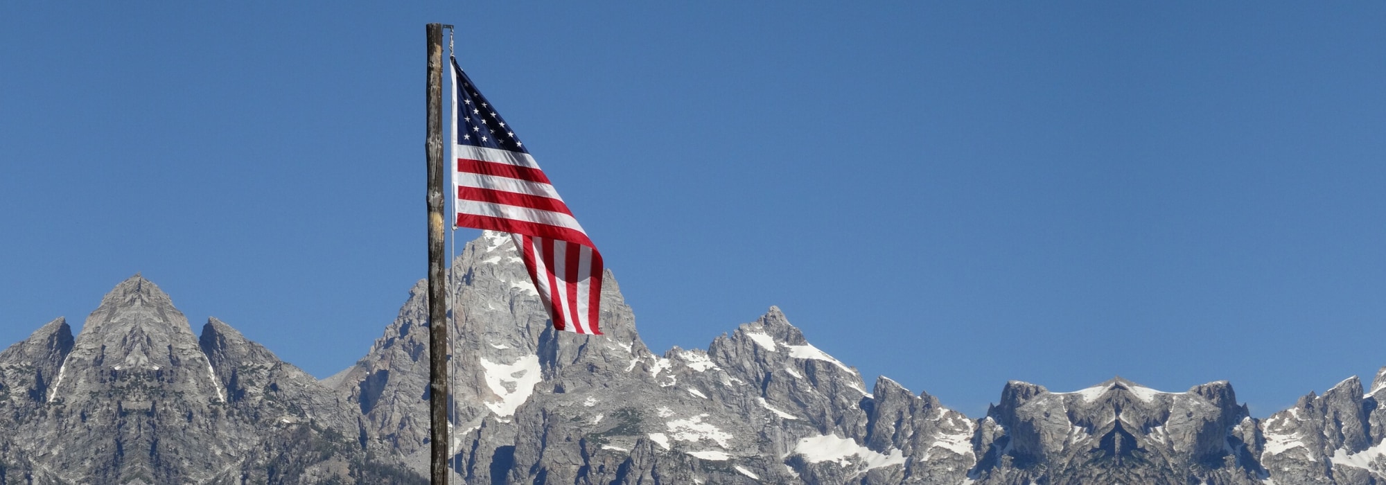 American Flag blowing in the wind by snowy mountain tops - Military offers and discounts at Bob Penkhus Volvo in Colorado Springs