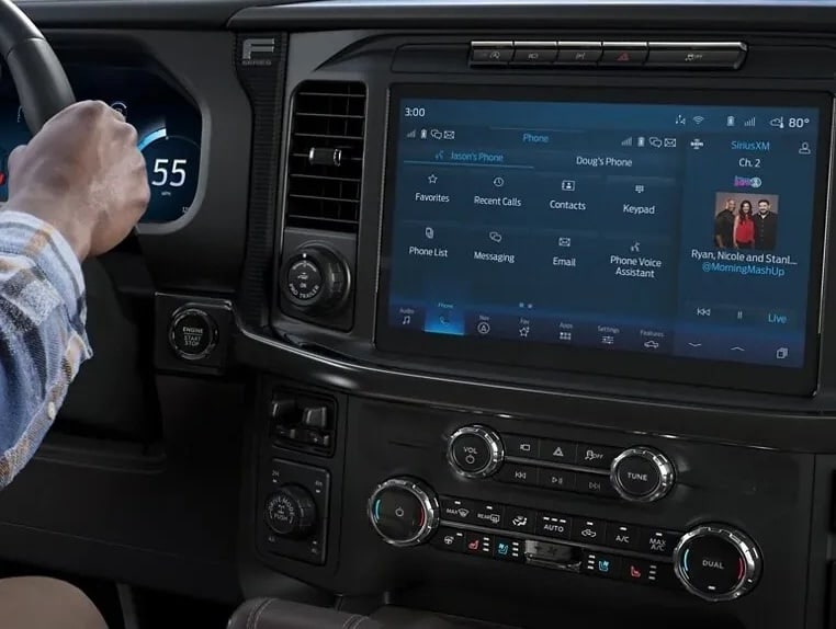 Two people exiting a 2025 Ford F-150® XLT pickup in Rapid Red hitched to a trailer of ATVs