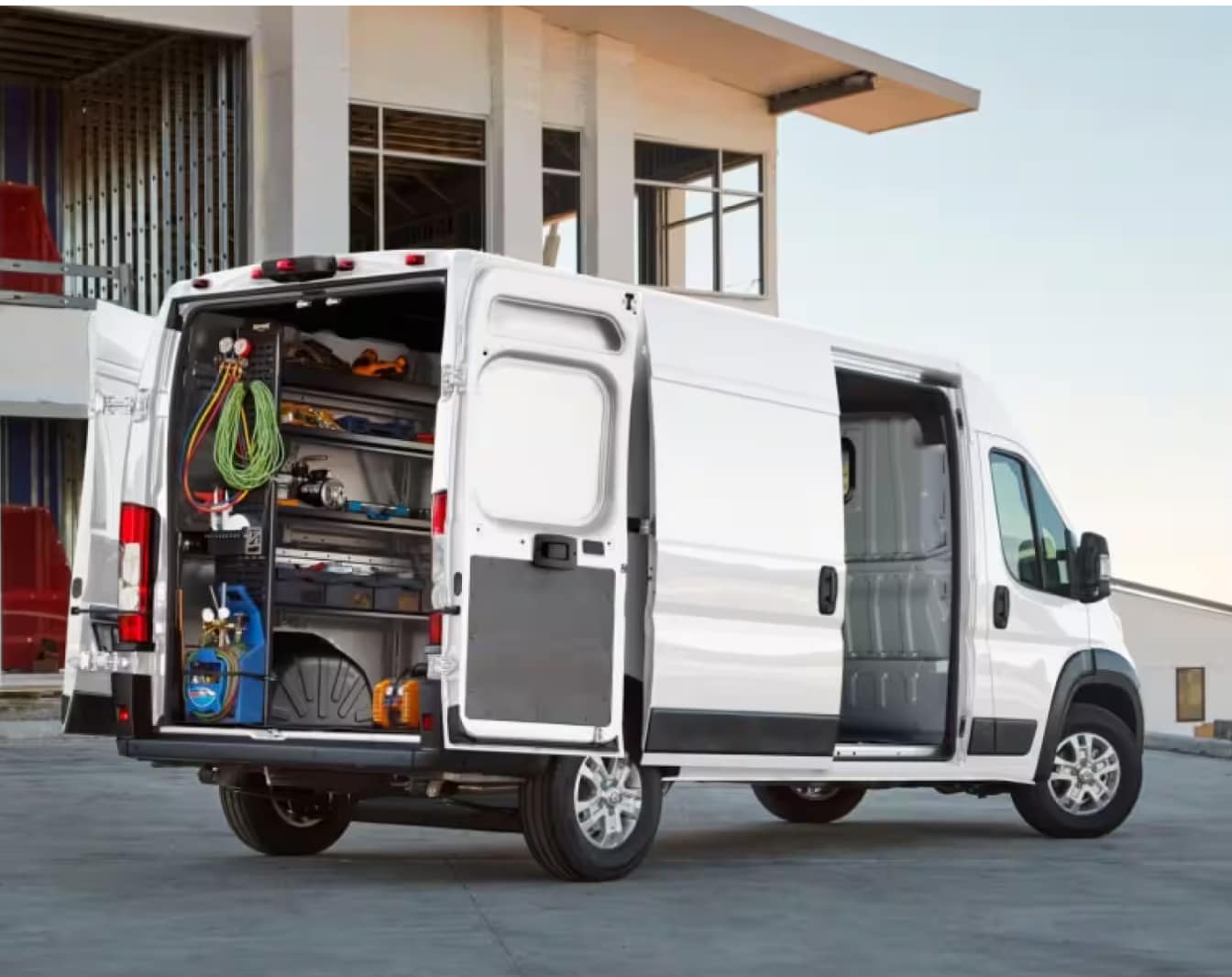 A white Ram Promaster parked with its doors opening showing work equipment.