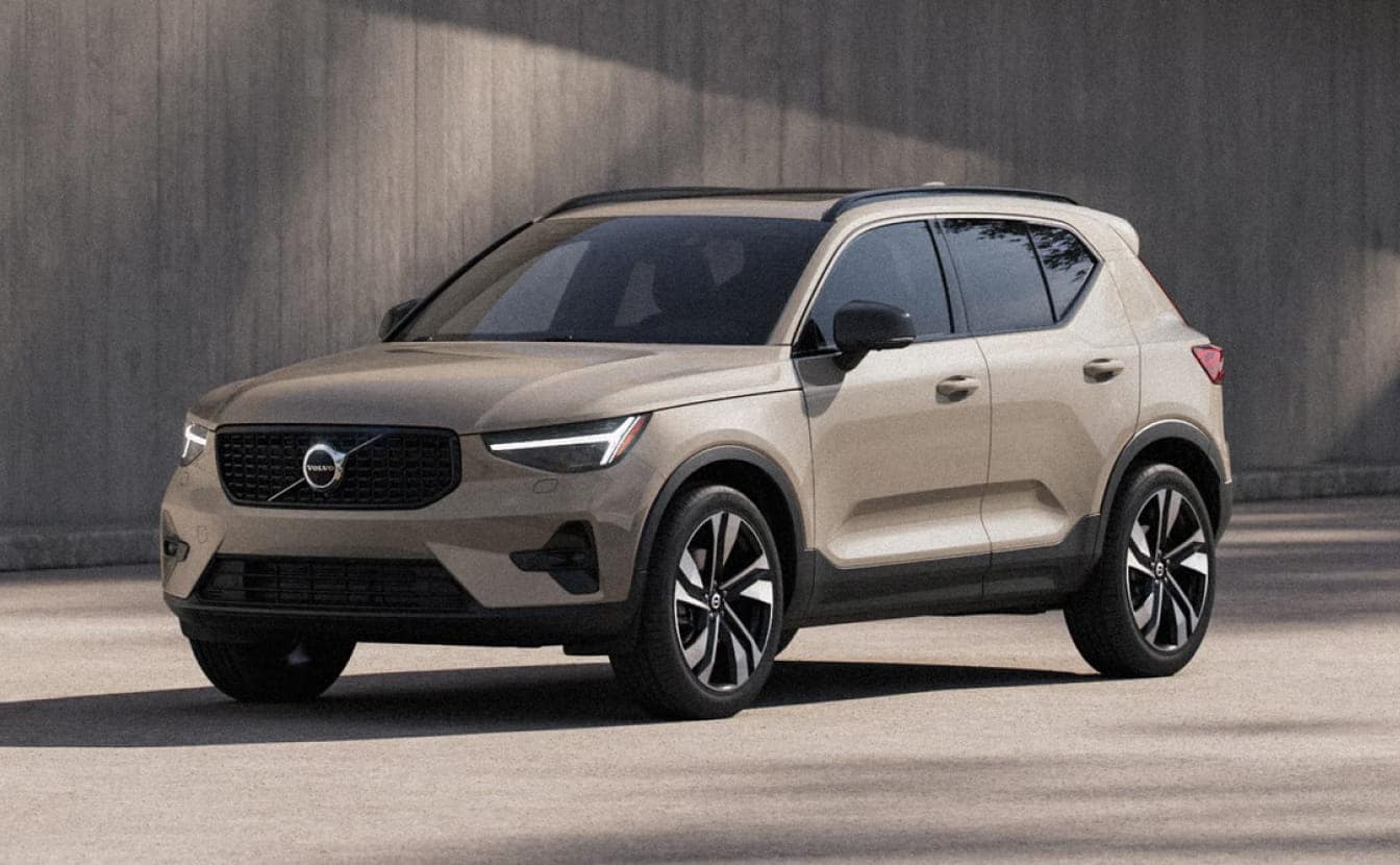 Beige Volvo XC40 shown from a front three-quarter angle against a modern concrete backdrop.