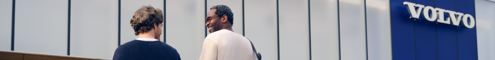 Two people walking towards a Volvo Dealership