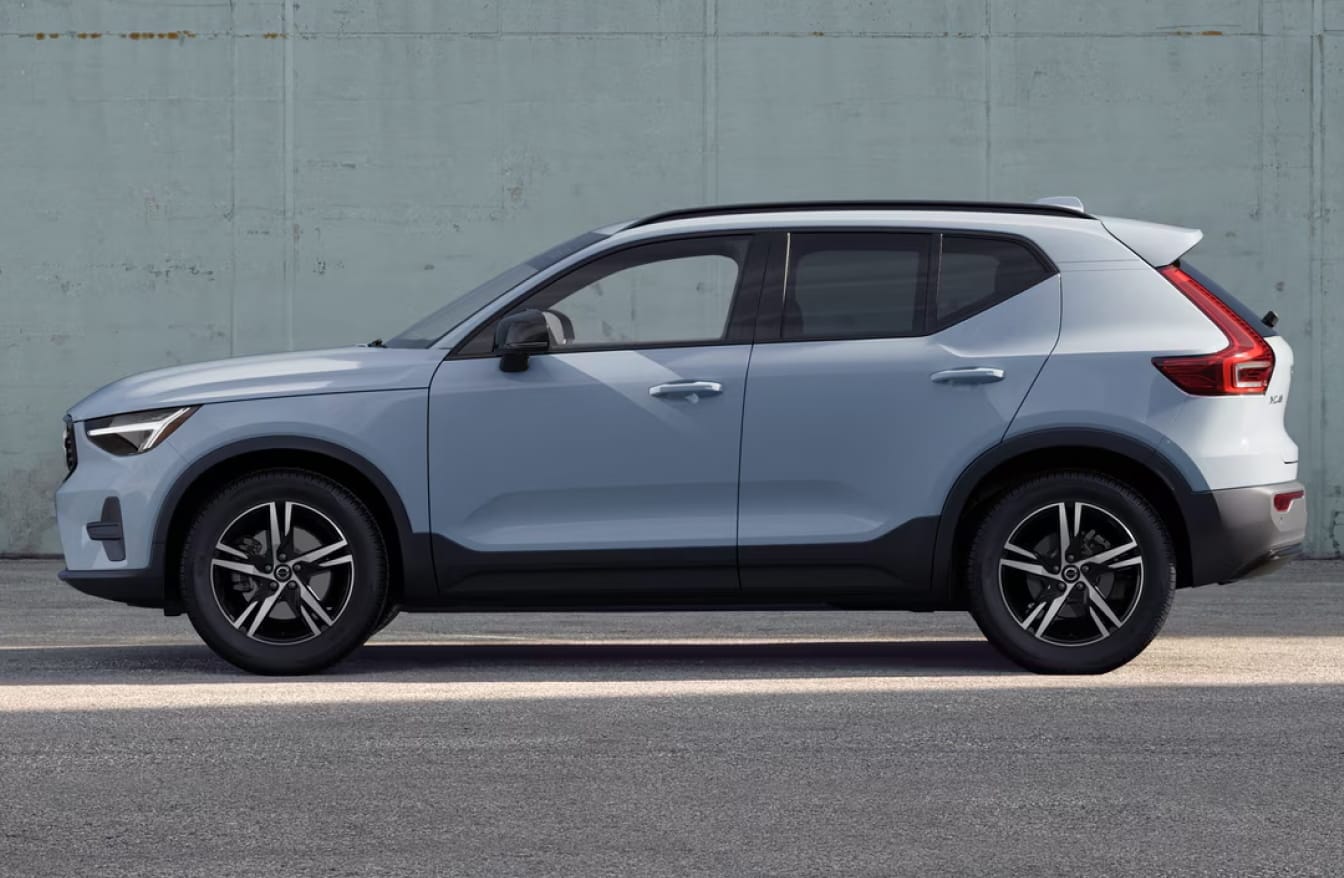 Side profile of a light blue Volvo XC40 parked against a concrete wall.