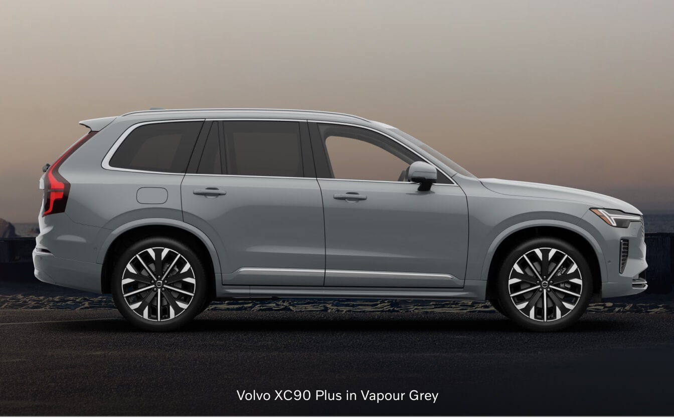 2026 Volvo XC90 Plus side profile view parked on a dark coastal roadway at dusk.