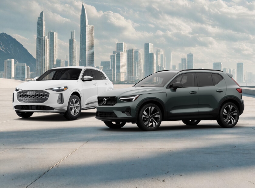 2026 Volvo XC40 Ultra in Forest Lake and Audi Q5 Premium in Arkona White, posed before a modern city skyline.