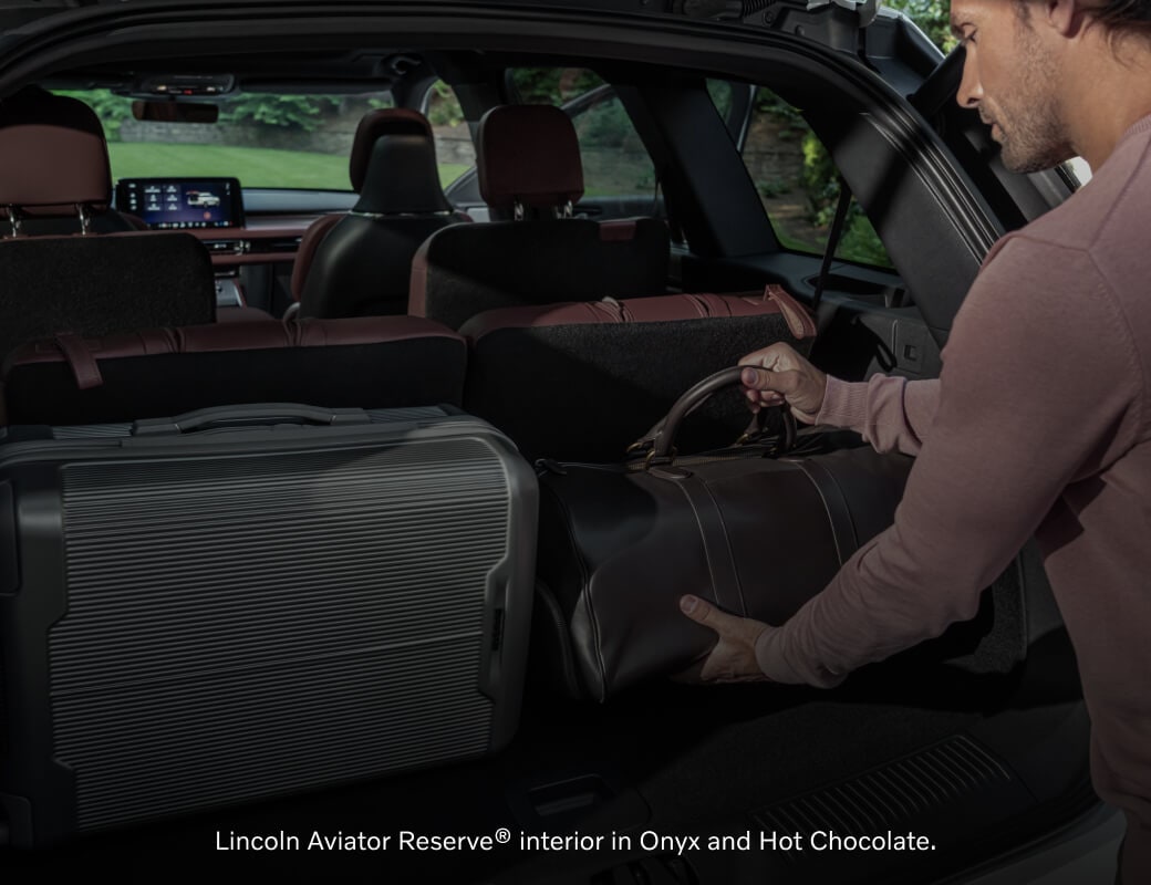 Cargo area view of an Onyx and Hot Chocolate leather Lincoln Aviator Reserve being loaded with luggage.