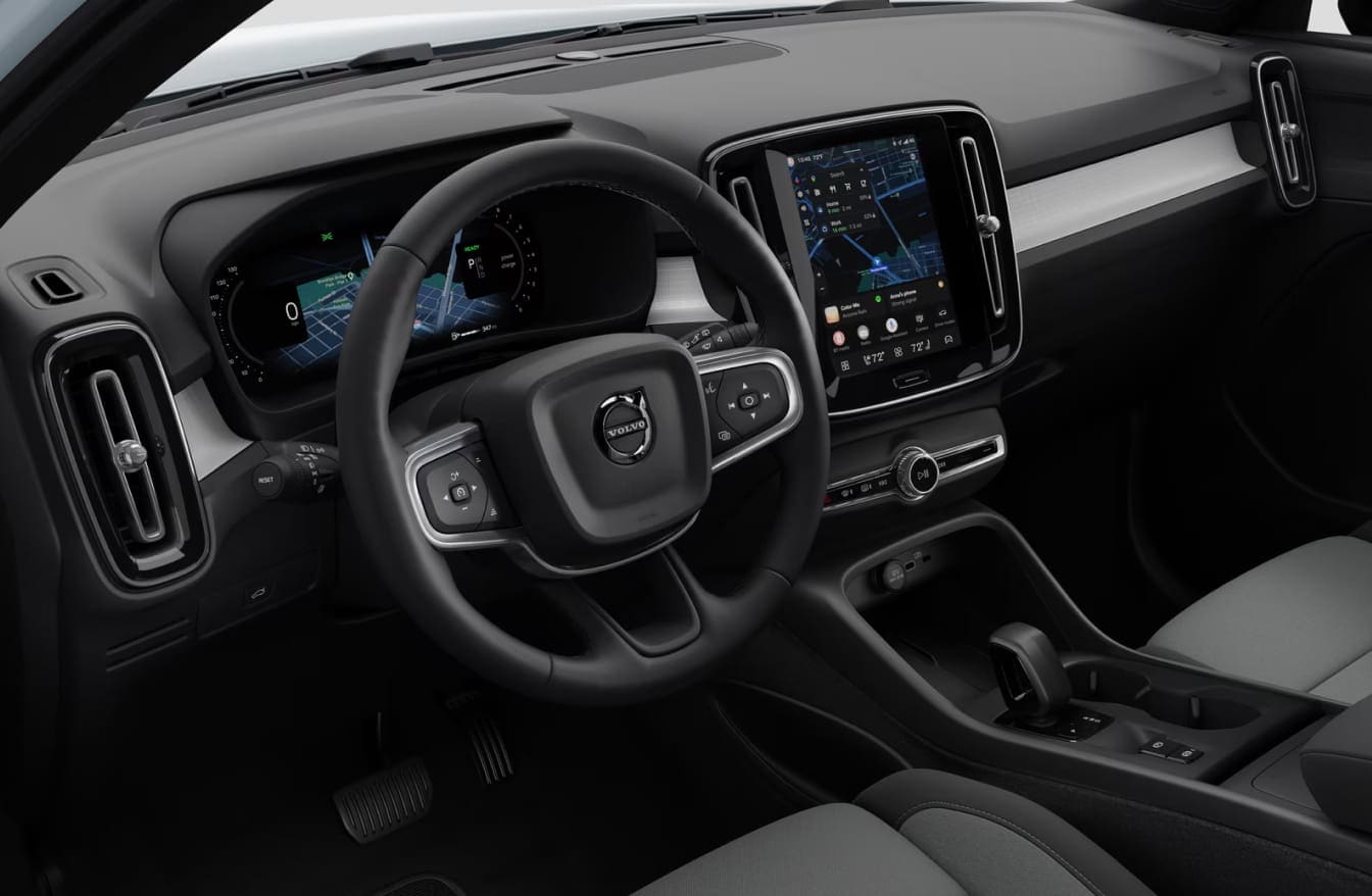 Close-up of the Volvo XC40 driver cockpit with digital instrument cluster, steering wheel, and vertical center touchscreen.